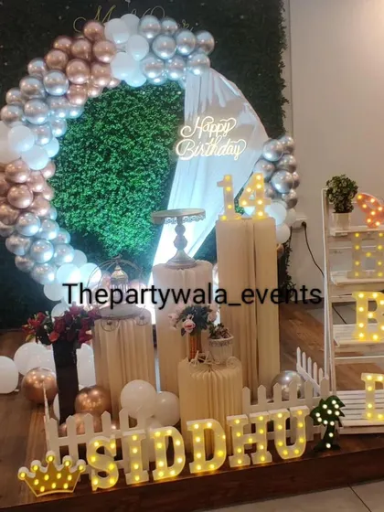 A modern ring decoration with a grass wall backdrop and a mix of rose gold, silver, and white balloons.