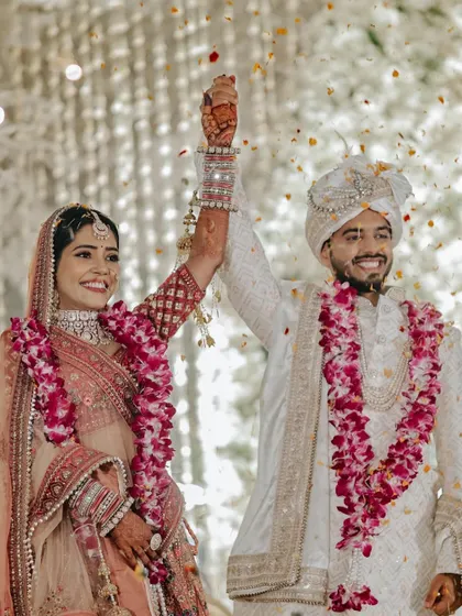 A moment of pure triumph and joy as the newlyweds, Akash and Nikita, raise their hands in celebration after the Varmala ceremony.
