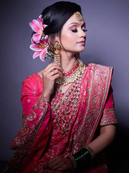 An elegant portrait of a bride in a pink saree, her hair adorned with a beautiful lily. This look is perfect for a reception or engagement.