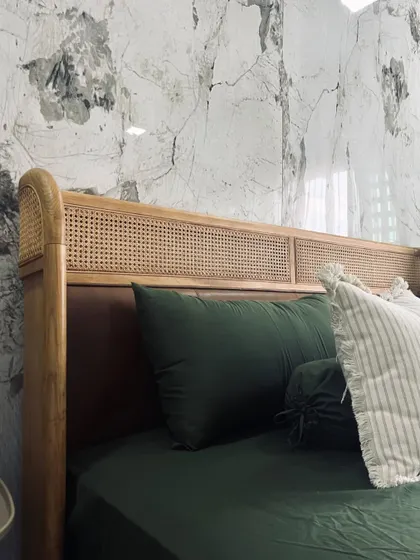 The Tierra Bed, styled with deep green linens against a striking marble wall. The combination of natural materials and bold decor highlights the bed's versatility and its ability to anchor a sophisticated bedroom design.