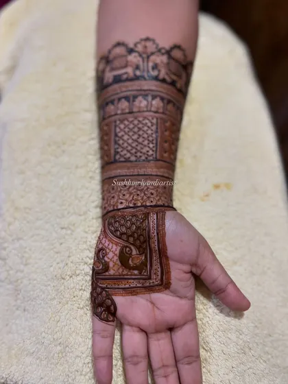 A closer look at the arm portion of a bridal design, showing the detailed elephant procession and checkerboard patterns.