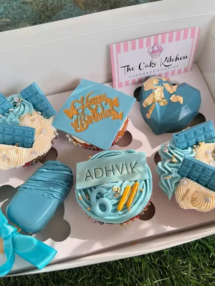 A custom-themed dessert box in shades of blue. This box includes cupcakes, cakesicles, and geometric chocolate hearts, all personalized for a birthday celebration.