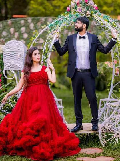 A fairy-tale moment with a Cinderella-style carriage. The couple's pose is straight out of a storybook, with the bride's ruffled red gown adding to the romantic fantasy.