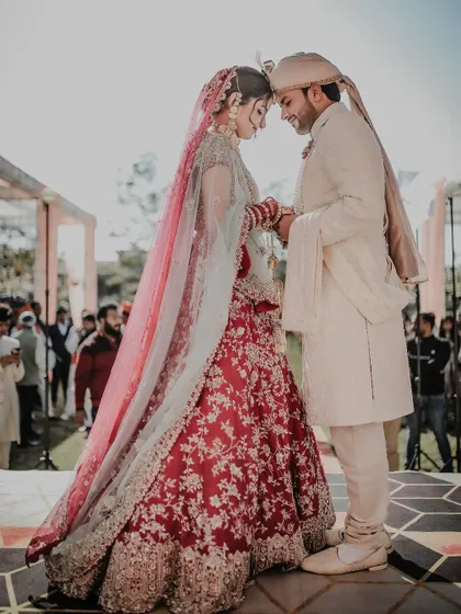A quiet, intimate moment between the bride and groom during their outdoor wedding ceremony. The backlighting from the sun creates a beautiful, ethereal glow, highlighting this special connection.