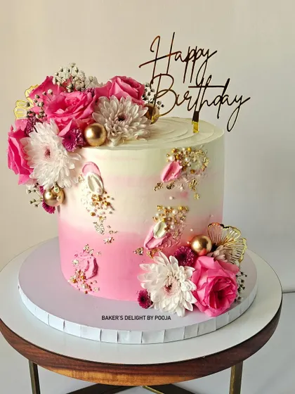 A gorgeous pink and white ombre cake for a 60th birthday celebration. Adorned with fresh flowers and golden accents, it's a perfect blend of elegance and charm for a special milestone.