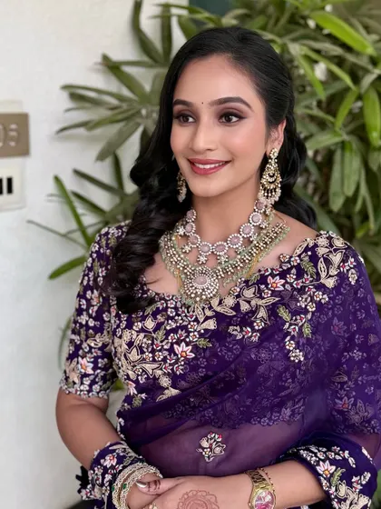 A side profile showing the elegant hairstyle and the beautiful details of her embroidered saree, complemented by soft, glowing makeup.