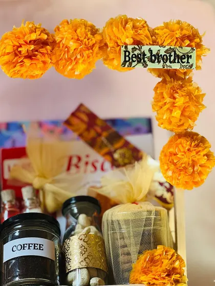 A close-up of the "Best brother" tag and marigold garland on the two-tiered Rakhi hamper.