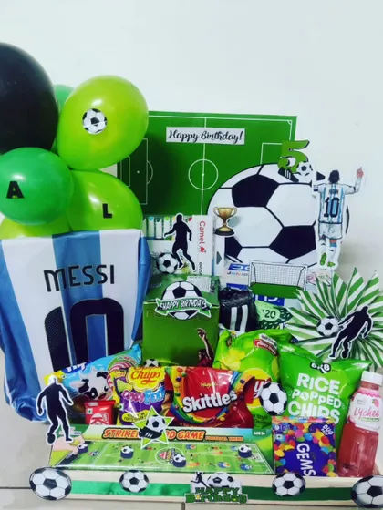 For the ultimate sports fan, I create theme-based hampers that celebrate their passion. This football-themed gift box for a Messi fan includes an Argentina jersey, themed snacks, balloons, and custom cutouts for a winning birthday surprise.