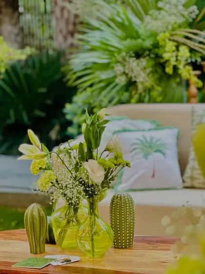 A close-up of the decor, showing the green-tinted vases, cactus props, and custom cushions with palm tree prints.