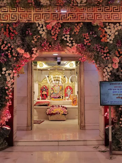 The entrance to the main sanctum of the temple, framed by a magnificent arch of pink, red, and white flowers, creating a divine and welcoming gateway for devotees.