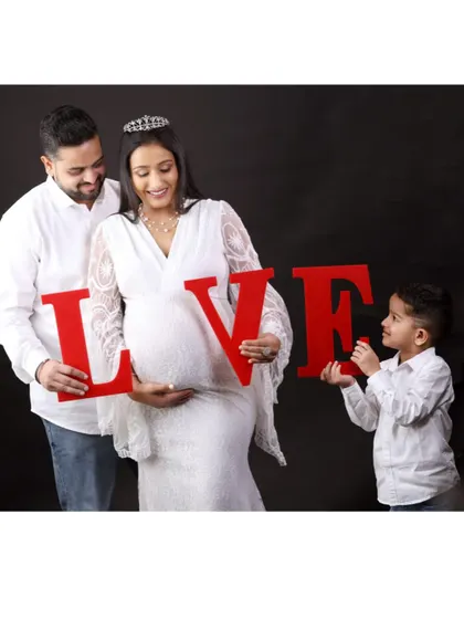 Spelling it out with love. The family holds up "LOVE" letters, with their son playfully taking part, creating a fun and heartwarming family maternity photo.