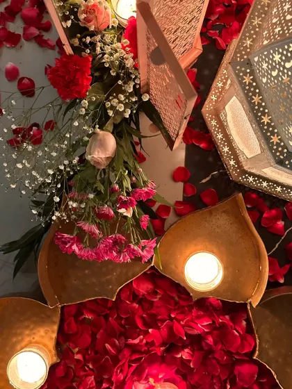 A close-up of decor details, including Moroccan lanterns and lotus-shaped candle holders filled with rose petals.