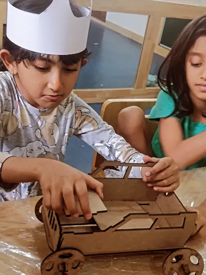 Teamwork in action as two students collaborate on building a wooden truck model.