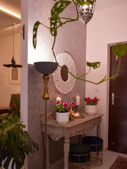 This foyer setup is all about greenery and light. The monstera plant and the floor lamp create a beautiful play of shadows on the textured wall.