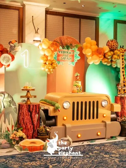 Vedika's first safari was a wild adventure. The main backdrop featured a safari jeep prop for the cake, a balloon arch in jungle colors, and cutouts of cute safari animals like a giraffe and hippo.