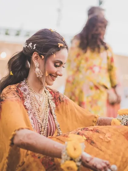 The bride enjoying a quiet, happy moment during her outdoor Haldi ceremony.