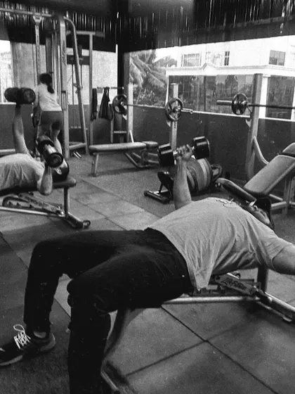 Two clients perform dumbbell presses side-by-side, showcasing the shared motivation in our gym.