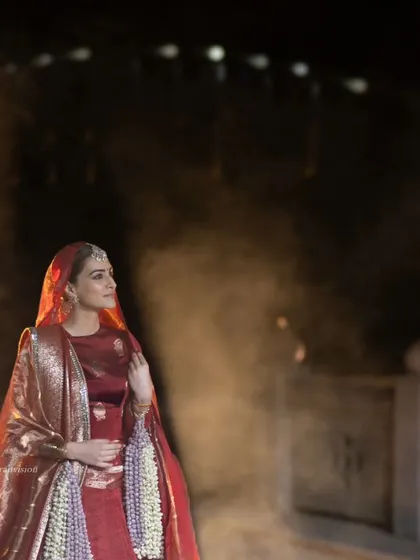A dreamy, atmospheric shot of Kriti Sanon with smoke and fireworks. This frame feels magical and highlights the spectacular setting of the fashion show.