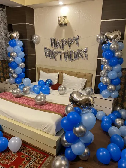 A close-up of the bed decoration with blue and silver balloon pillars and heart-shaped foil balloons.