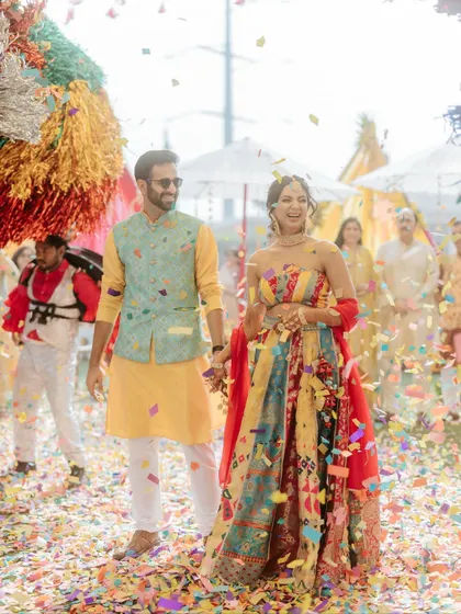 The couple walks hand-in-hand through a shower of colorful confetti, a moment of pure magic.