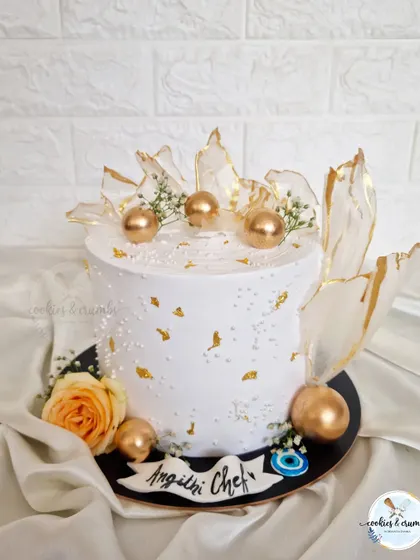 This white and gold cake is pure elegance. I used rice paper sails with gold edges, fresh flowers, and an evil eye charm for a modern and artistic touch.