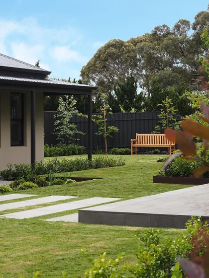 A view from the side of the house, showing how the stepping stones lead from the patio area across the lawn. The design is simple, elegant, and highly functional.