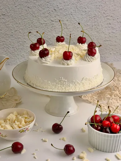 The White Forest Gateau, a delicate alternative with soft vanilla layers, white chocolate shavings, and cherries.