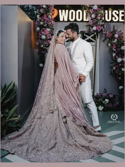 A regal portrait of the couple at their reception. The bride's magnificent velvet lehenga and the groom's classic white sherwani create a look of timeless elegance and sophistication.