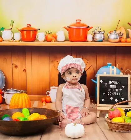 A full view of the nine-month kitchen setup, showing the baby sitting among the props.