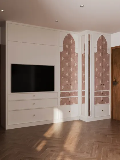 The custom wardrobe in this bedroom features traditional Indian arched motifs on the doors, blending seamlessly with the room's overall aesthetic. The unit also incorporates a media console for the TV.