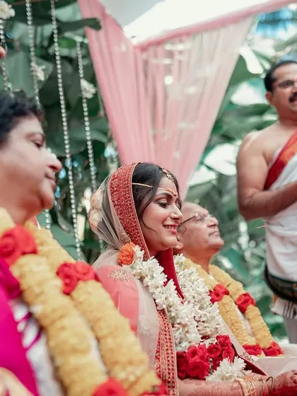 A candid shot of the bride smiling during her wedding ceremony, surrounded by her proud family members.