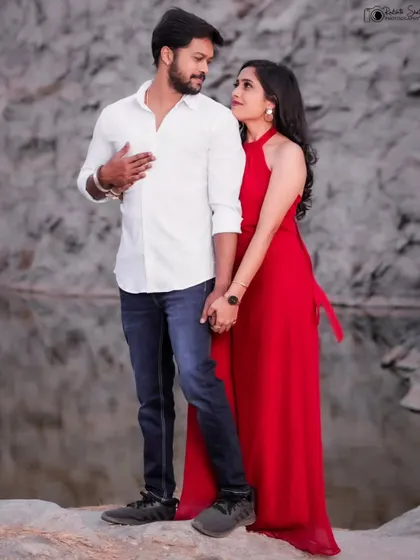 A sweet and simple pre-wedding photo. The couple holds hands, sharing a look of love and understanding. The natural setting and their casual attire make this a very relatable and heartfelt portrait.