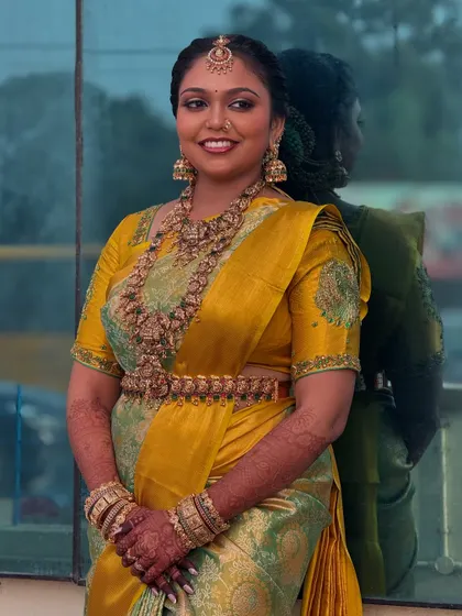 A beautiful portrait of my bride Prithivi against a reflective surface. Her makeup is perfectly balanced, with defined eyes and a lip colour that complements her dusky skin and vibrant saree.