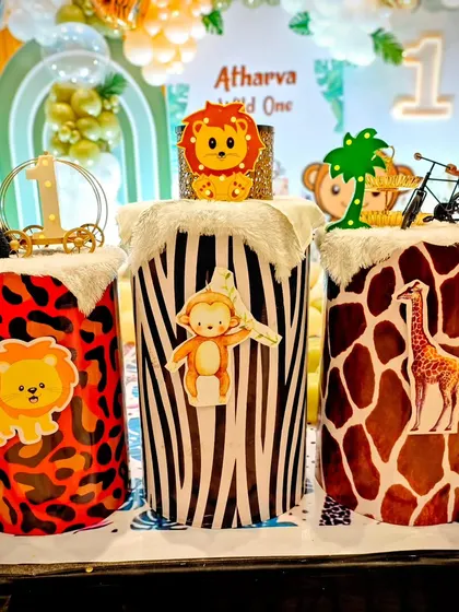 A closer look at the animal-themed pedestals for Atharva's first birthday. Each one is wrapped in a different animal print like leopard, zebra, and giraffe, and topped with adorable jungle character cutouts.