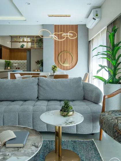 This shot highlights the comfortable, deep-cushioned grey sofa and nested marble-top coffee tables. In the background, the dining area's feature wall with a Buddha motif adds a sense of tranquility to the entire space.
