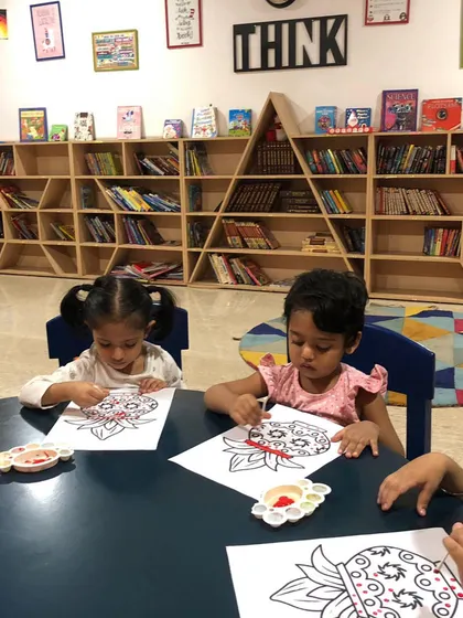 Two girls concentrating on their painting. This was part of a festival craft session where they were decorating images related to Indian culture.