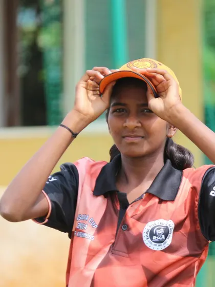A young female cricketer adjusts her cap, ready for action in the Dasara Cup.