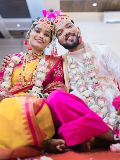 A happy, low-angle shot of the couple, capturing their smiles and the vibrant colors of their traditional Maharashtrian wedding attire.