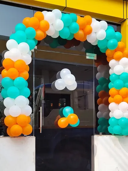 This balloon arch was created for a glass storefront entrance. The orange, white, and teal colors provide a vibrant and welcoming look for customers.