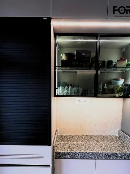 This unit combines a roller shutter for appliances with glass-fronted display cabinets. The internal lighting in the display section turns everyday crockery into a design feature.
