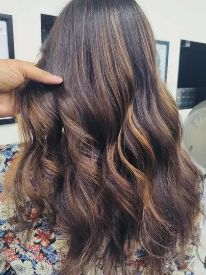 Our stylist demonstrates a finished caramel balayage. The highlights are strategically placed to add brightness around the face and through the lengths for a natural, flattering effect.