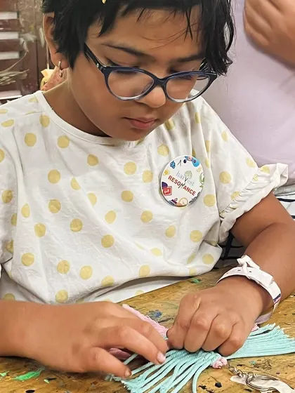 This young artist is carefully tying knots to create a macrame keychain. These small projects are a great way to learn the basics and get a quick sense of accomplishment.
