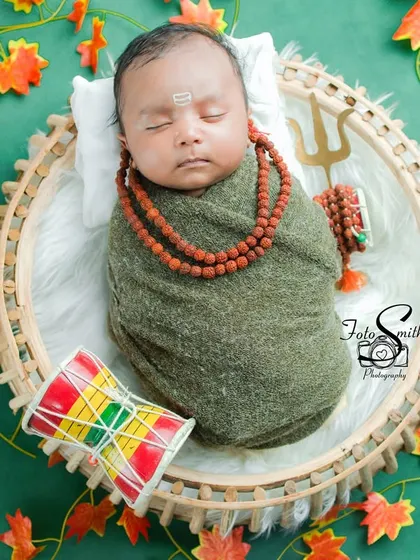 A sleeping newborn wrapped snugly, embodying the peaceful spirit of Shiv. The Rudraksha beads and Trishul add authentic details to this serene and spiritual setup.