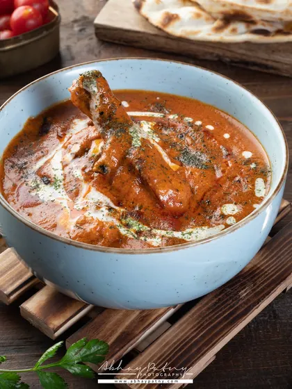 Another angle of a classic chicken curry. This shot focuses on the chicken leg piece, making it the hero, and uses a rustic wooden prop to add to the traditional feel.