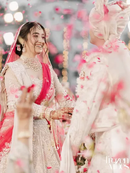 A candid shot of the couple laughing amidst a shower of pink petals. This image is full of life, movement, and happiness, perfectly capturing the celebratory mood.