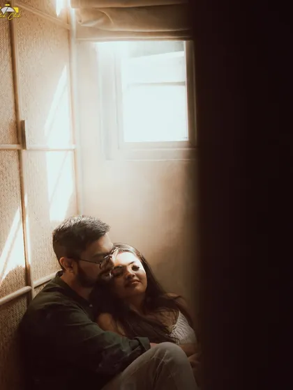 An intimate and moody shot of a couple in a sunlit corner, the light creating a beautiful, hazy effect.