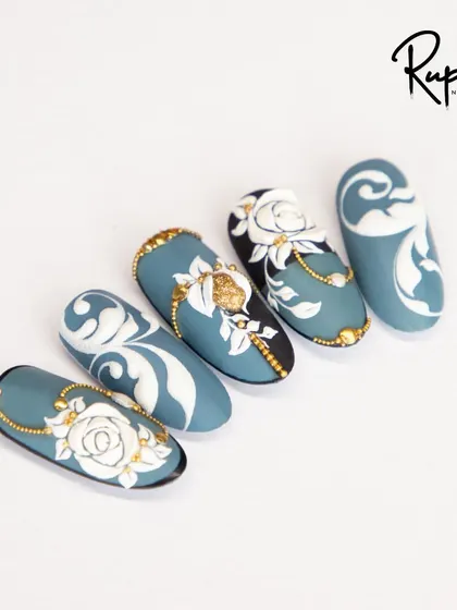 An elegant set combining 3D white roses, baroque swirls, and delicate gold jewelry accents on a muted blue base.