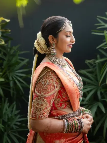 This bride is the picture of elegance in a red and cream bridal saree. The blouse is heavily embroidered with traditional motifs, while the sheer net back adds a subtle, modern detail.