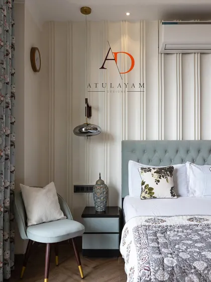 This angle shows the cozy reading chair and floral curtains that complement the serene blue and white color scheme of the bedroom.