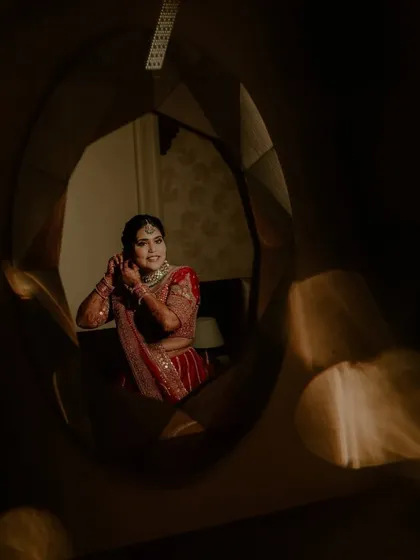 A bride getting ready, captured in a mirror's reflection with beautiful, soft lighting.
